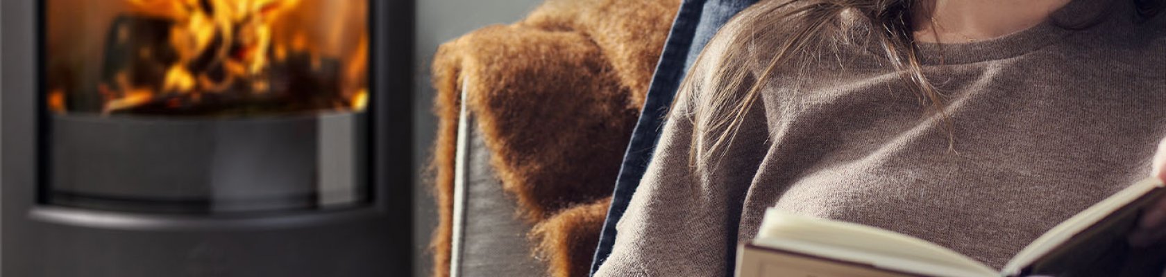 Dame sidder foran brændeovnen Jøtul F 373 Advance