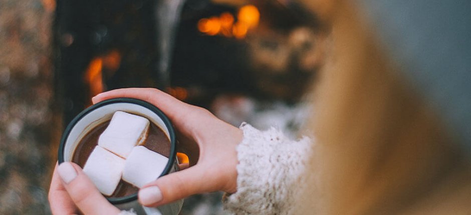 Pige drikker kakao ved bålet