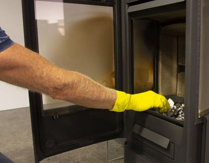 Mand, der renser brændeovnen Jøtul F 233 med aske og vand 