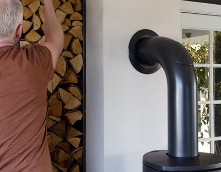 Mann som tar ved for at legge i peisen