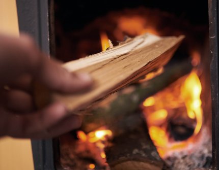 Hånden der sætter træet i pejsen