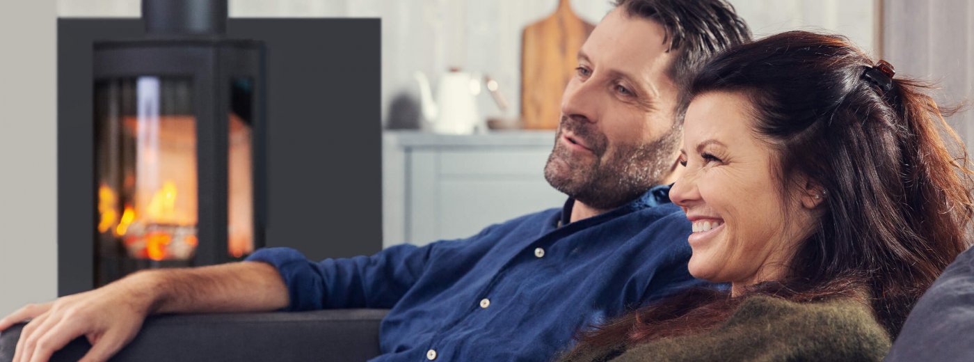 Mand og kvinde sidder foran brændeovnen Jøtul F 373 Advance i stuen