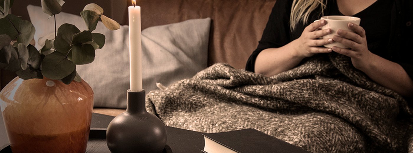 Pige sidder på en brun sofa med en kop te