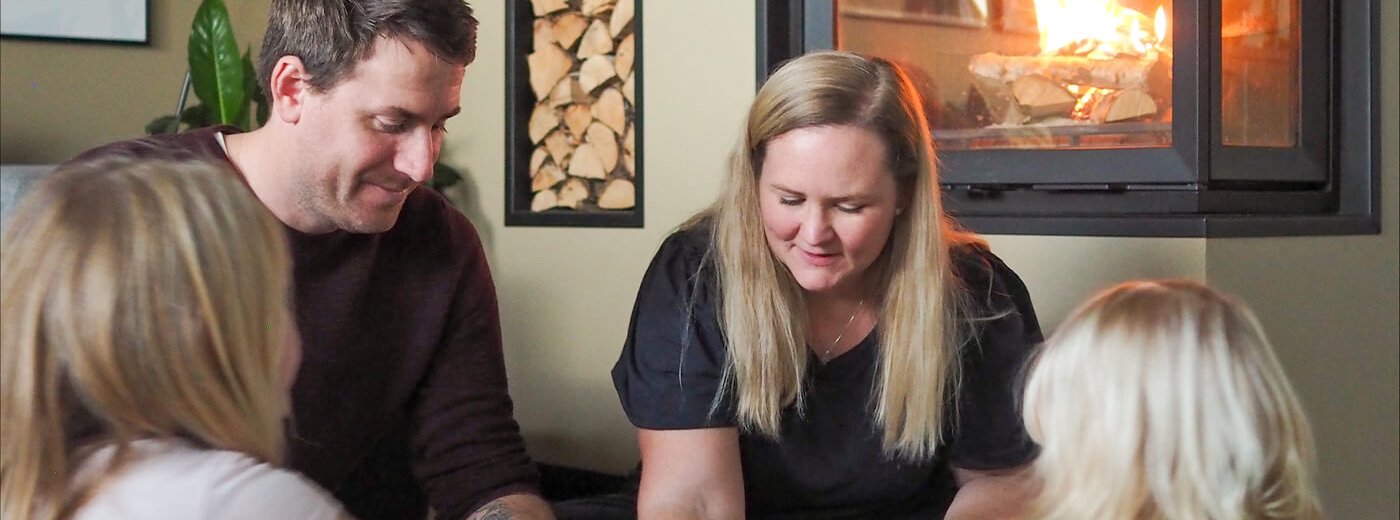 Karoline og familien sidder og spiller spil foran Jøtul I 620 FR pejseindsatsen