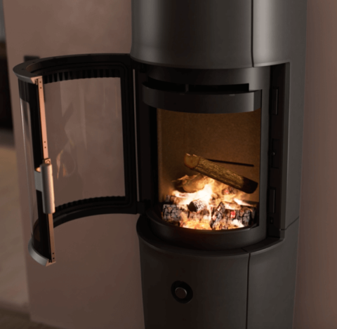 Moderne værelse med stor sort Jøtul F 174 brændeovn med åben dør, pudderlilla vægge