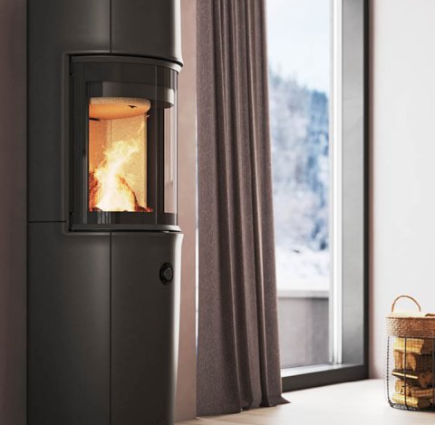 Moderne værelse med stor sort Jøtul F 176 brændeovn, pudderlilla vægge og sneklædt bjergudsigt