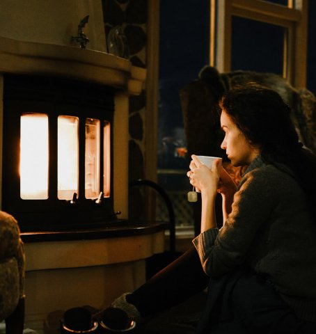 Dame sidder foran pejsen om aftenen